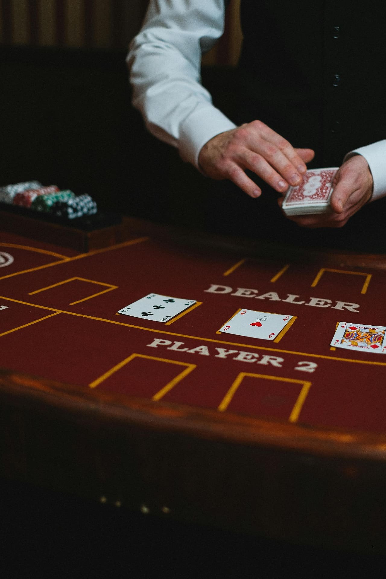 Dealer holding deck over red felt table