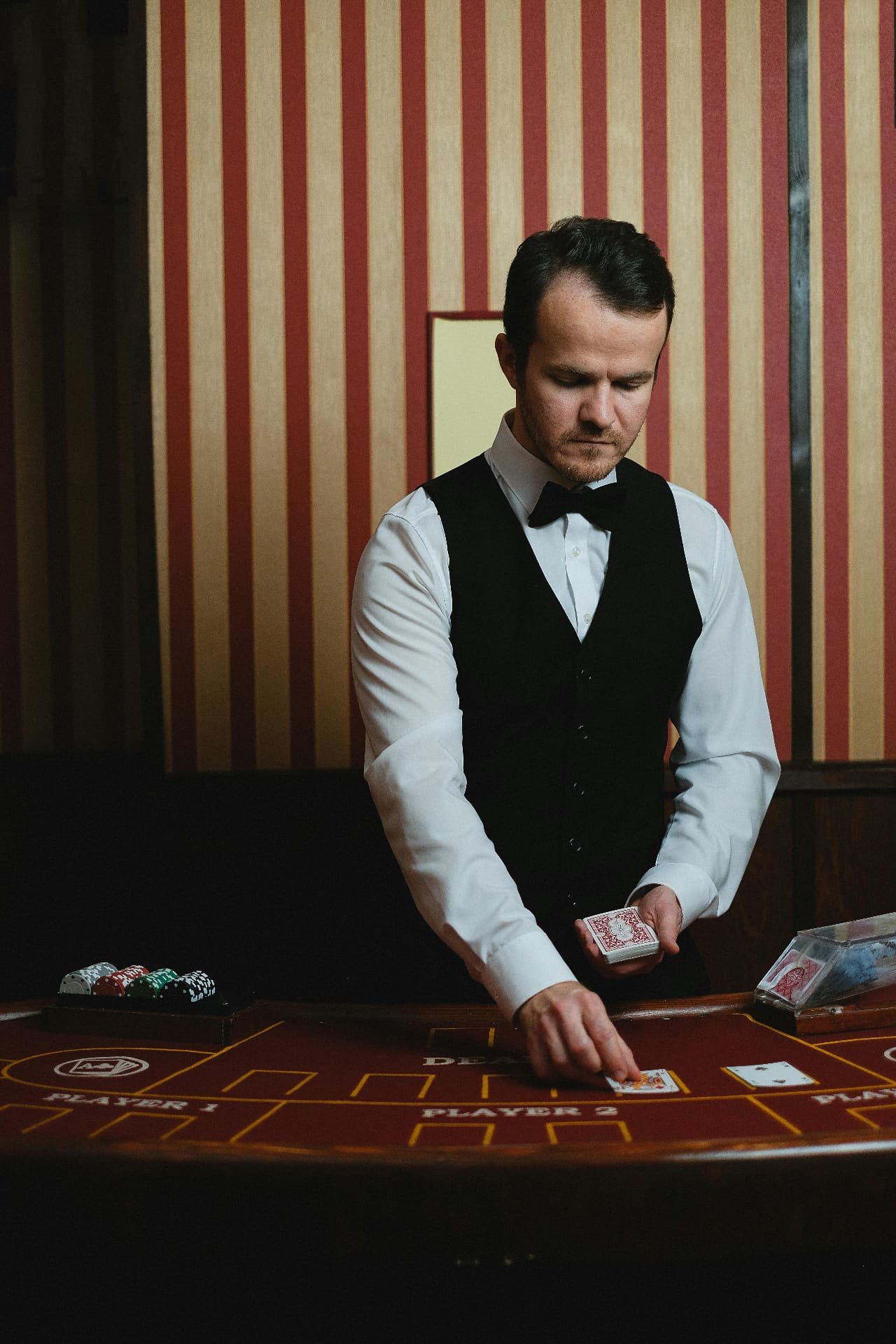 Dealer in bow tie dealing cards at table